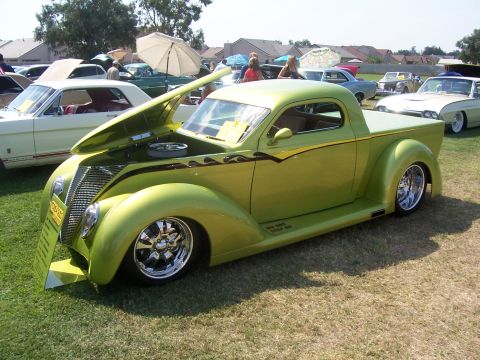 2002 Ford Mustang - Custom hot rod pickup truck with flames and a unique grille, displayed at a car show.