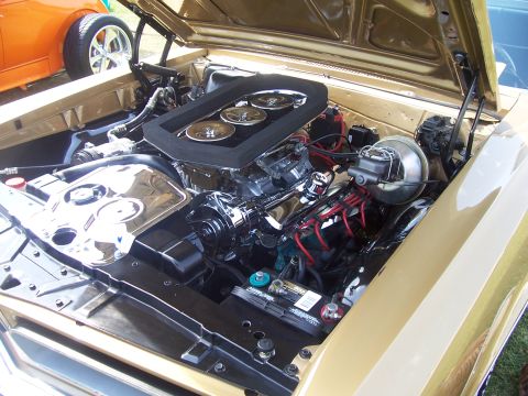 2002 Ford Mustang - A detailed view of a gold engine bay, chrome components and an aftermarket air intake system. Another vehicle is partially visible on the l…