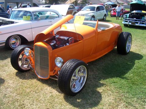 2002 Ford Mustang - Custom orange roadster displayed at a car show with other vehicles present.