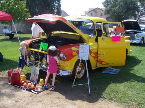 2002 Ford Mustang - A vintage yellow Chevrolet pickup truck, customized with flames, is displayed outdoors with dolls and other items.