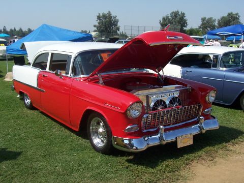 2002 Ford Mustang - A classic red and white 1955 Chevrolet sedan is displayed with its hood open at an outdoor event.
