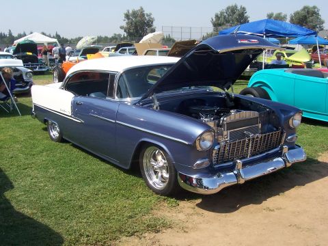 2002 Ford Mustang - A classic 1955 Chevrolet Bel Air is displayed at an outdoor car show with other vehicles present.