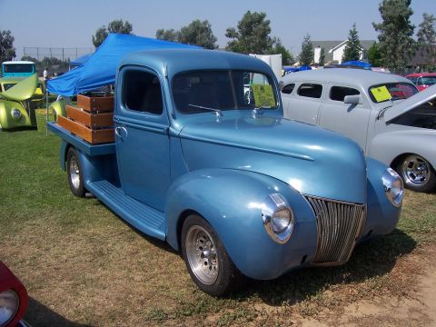 2002 Ford Mustang - A classic blue pickup truck is displayed at an outdoor car show with other vehicles present.