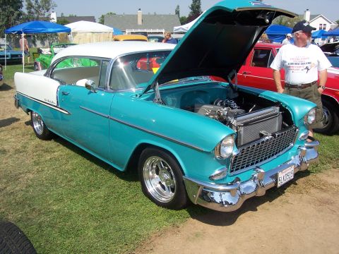 2002 Ford Mustang - A turquoise and white 1955 Chevrolet Bel Air coupe is displayed with its hood open, revealing the engine bay.