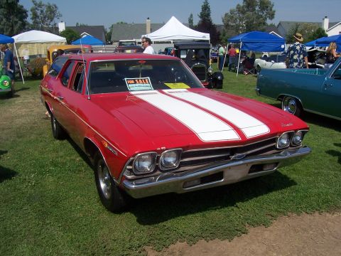 2002 Ford Mustang - A red 1969 Chevrolet station wagon is displayed at an outdoor event with a 'For Sale' sign in the window.