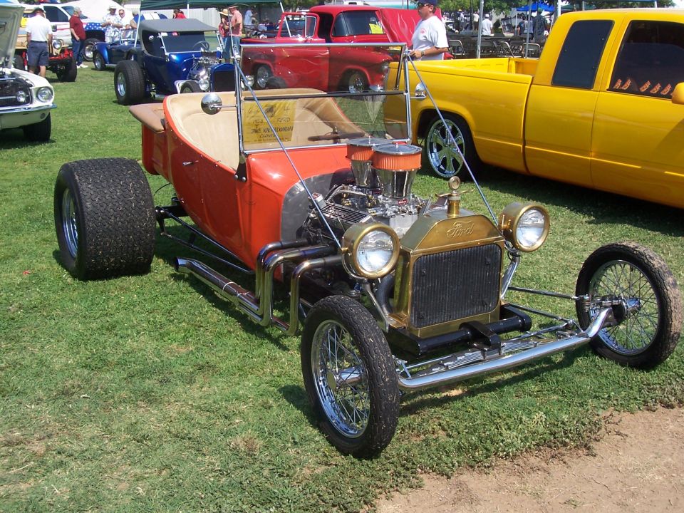Orange hot rod with gold grille and exposed engine, front view