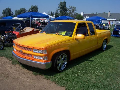 2002 Ford Mustang - Custom painted pickup truck displayed at an outdoor event with other vehicles present.