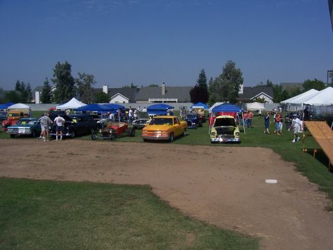 2002 Ford Mustang - An outdoor car show displays various vehicles and tents on a sunny day.