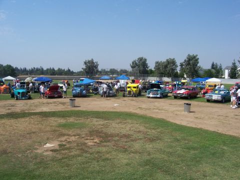 2002 Ford Mustang - A sunny day at a car show features a variety of vintage vehicles displayed on a grassy field.