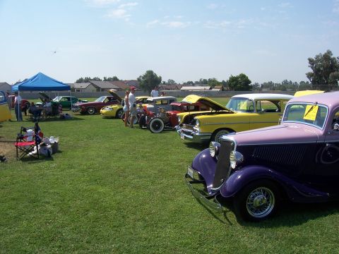 2002 Ford Mustang - A collection of vintage automobiles are displayed on a grassy field under a bright, sunny sky.