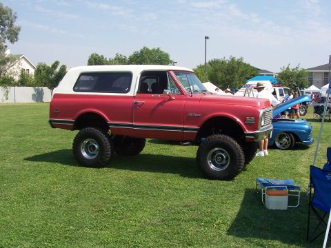 2002 Ford Mustang - This lifted K5 Blazer, likely from the early 1970s, is displayed on a grassy field alongside other vehicles.