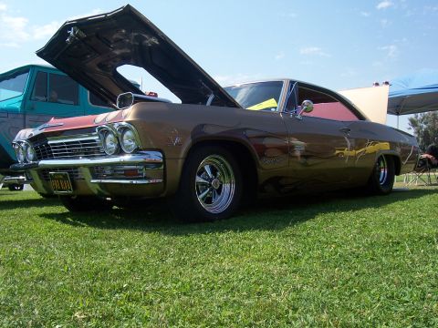 2002 Ford Mustang - Customized 1965 Chevrolet Impala with flames and open hood, seen at an outdoor event.