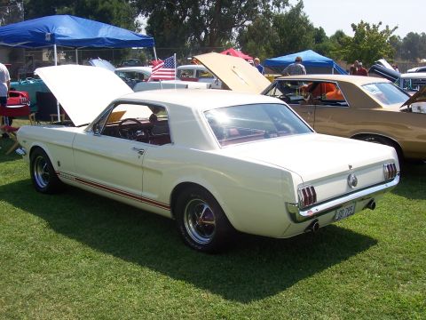 2002 Ford Mustang - A classic white Ford Mustang is displayed at an outdoor event, with its hood open to reveal the engine bay.