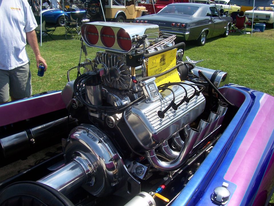 Supercharged V8 engine with chrome valve covers and triple carburetors in a boat