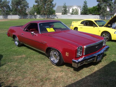 2002 Ford Mustang - A red El Camino is parked on grass next to a yellow Ford Mustang. The El Camino appears to be from the late 1970s.