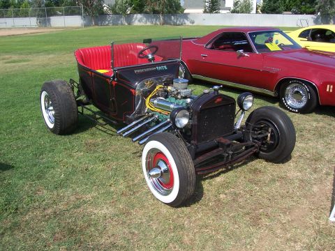 2002 Ford Mustang - A custom hot rod sits on display next to other vehicles at an outdoor event.