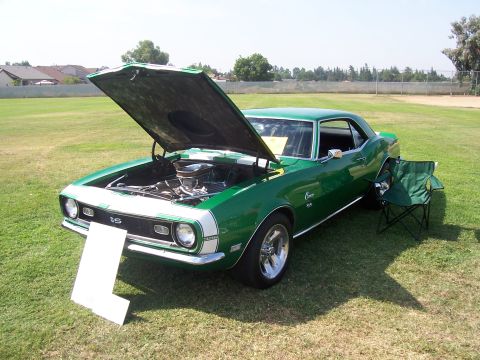 2002 Ford Mustang - A green classic car with its hood open is parked on a grassy field with a folding chair next to it.