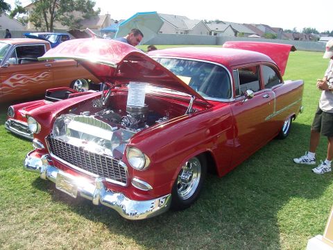 2002 Ford Mustang - A red 1955 Chevrolet sedan is displayed with its hood open, revealing the engine bay.