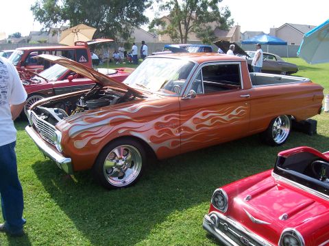 2002 Ford Mustang - Customized orange pickup truck with flame graphics is displayed at an outdoor event.
