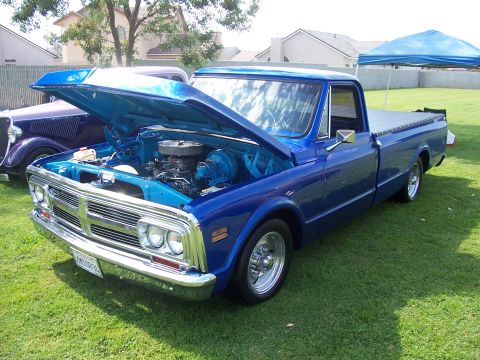 2002 Ford Mustang - A blue pickup truck is parked on a grassy lawn with its hood open, revealing the engine compartment.