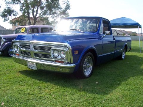 2002 Ford Mustang - A blue pickup truck from the 1970s is parked on a grassy lawn next to another vintage vehicle.