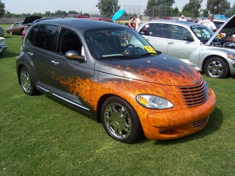 2002 Ford Mustang - A customized Chrysler PT Cruiser with a flame paint job is displayed on a grassy field next to other vehicles.
