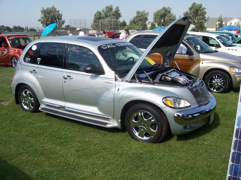2002 Ford Mustang - A customized silver PT Cruiser is displayed outdoors with its hood open, revealing the engine bay.
