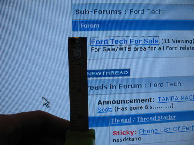 Computer screen displaying a Ford Tech forum with a ruler and hand in foreground