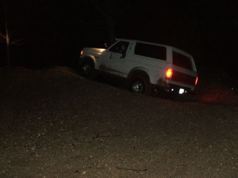 1989 Ford Bronco - White SUV navigates a dark, dirt incline at night.