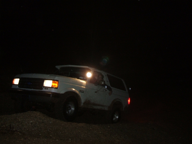 White 1989 Ford Bronco driving at night
