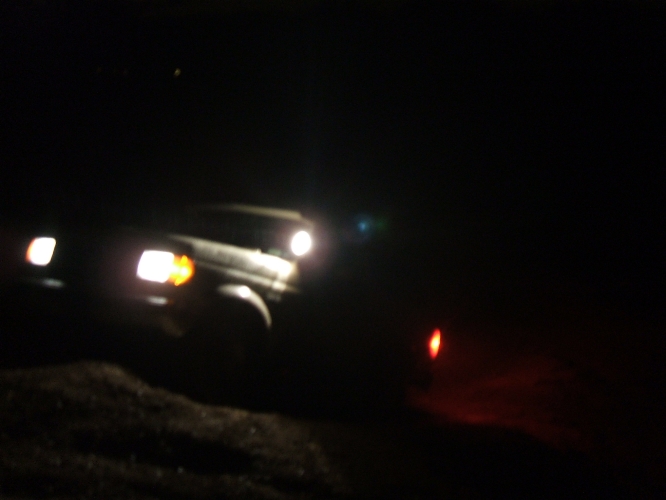 SUV with headlights on driving in the dark