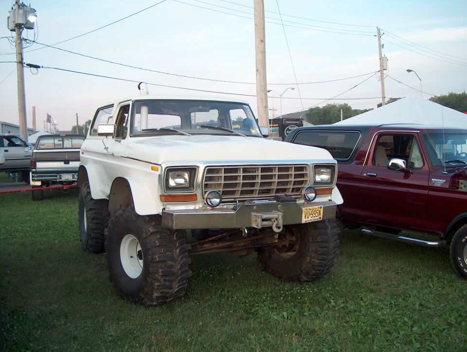 White lifted vintage Ford Bronco on large tires at an outdoor show