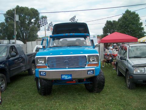 1978 Ford Bronco - A lifted blue 1978 Ford Bronco, identified as 'Blue Thunder', is parked at a meet with other vehicles.