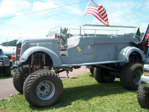 1978 Ford Bronco - A heavily modified truck with oversized wheels and an American flag is parked on a grassy field.