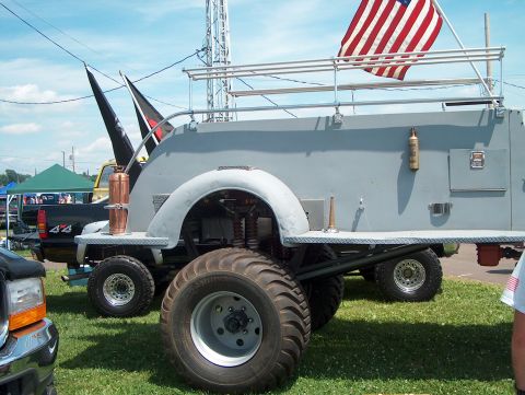 1978 Ford Bronco - Custom truck with large tires and American flag on roof rack at an outdoor event.