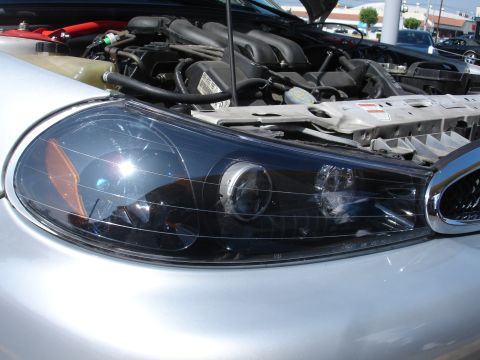 1993 Ford Taurus - Close-up of a car's headlight and engine compartment, hood is open.