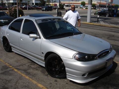 1993 Ford Taurus - Silver sedan with SVT banner and custom body kit, parked outdoors with a man standing nearby.