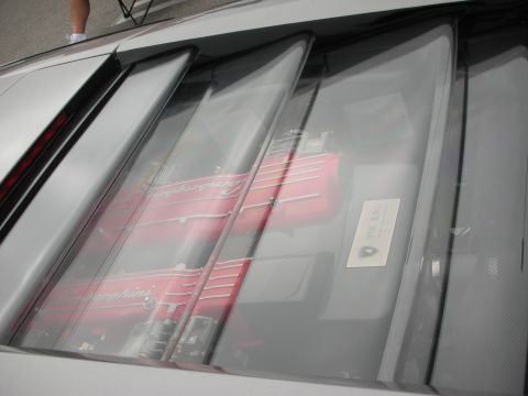 1998 Ford Crown Victoria - The engine cover of a Lamborghini reveals its red engine components through a series of louvers, with a small plaque visible on the right.