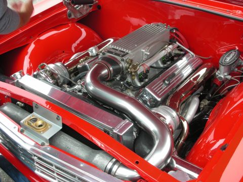 1998 Ford Crown Victoria - The engine compartment features a polished intake manifold and valve covers, with bright red paint on the surrounding body panels.