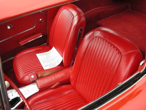 1998 Ford Crown Victoria - The interior of a classic car shows red vinyl seats and carpeting, with a document placed on the passenger seat.
