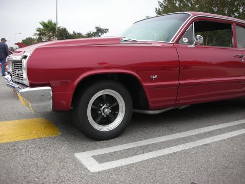 1998 Ford Crown Victoria - A red classic car is parked in a lot, showing its front quarter panel and wheel.