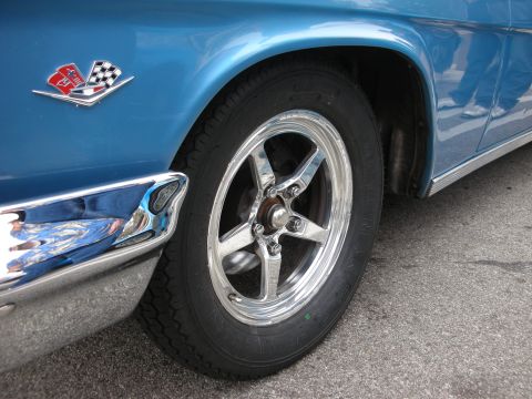 1998 Ford Crown Victoria - Close-up of a blue car's fender, chrome trim, and a racing flags emblem.