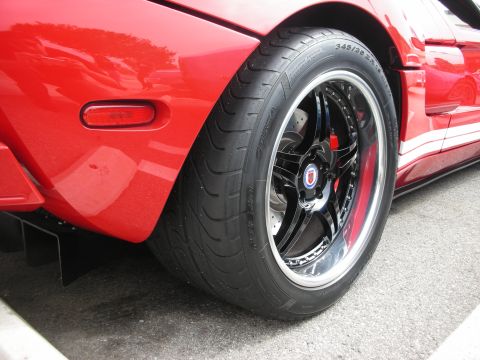1998 Ford Crown Victoria - Rear wheel detail of a red sports car, showing custom rims and performance tires.