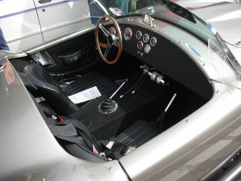 1998 Ford Crown Victoria - The interior of a silver sports car features a wooden steering wheel, racing seat, and a fire extinguisher mounted on the dashboard.