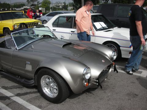 1998 Ford Crown Victoria - A silver Shelby Cobra replica is parked at a car meet with other vehicles visible.
