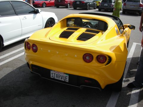 1998 Ford Crown Victoria - A yellow Lotus Elise is parked in a lot with other vehicles visible.