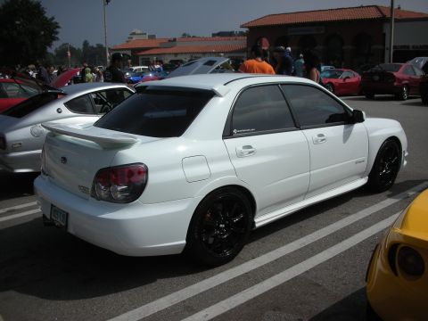 1998 Ford Crown Victoria - A white Subaru Impreza WRX STI is parked at an outdoor event with other vehicles.