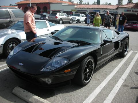 1998 Ford Crown Victoria - A black Ford GT is parked in a parking lot, with other vehicles and people in the background.