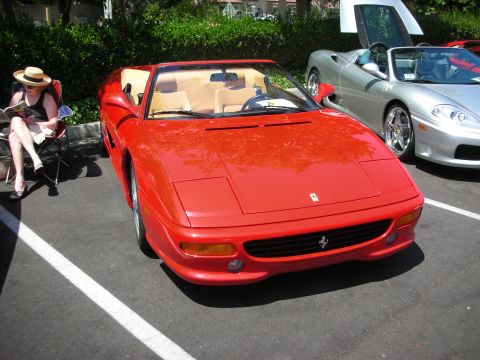 1998 Ford Crown Victoria - A red convertible sports car is parked in a lot next to a silver sports car, with a woman relaxing in a chair nearby.