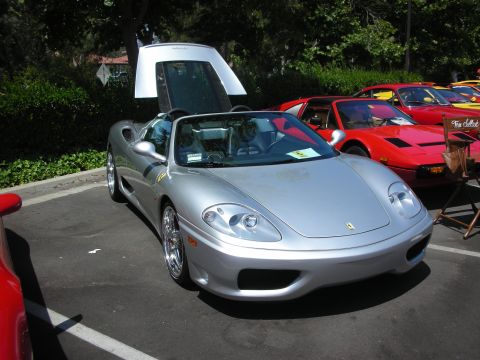 1998 Ford Crown Victoria - A silver convertible sports car is parked with its doors open, alongside other vehicles at an outdoor event.